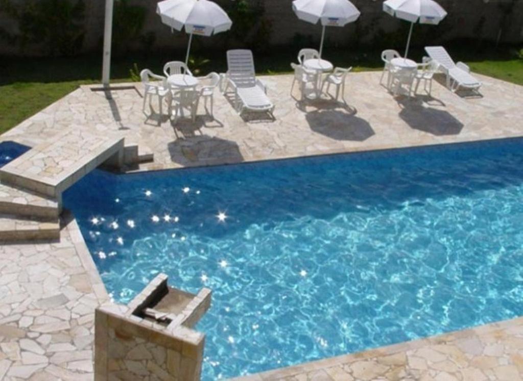 uma piscina com cadeiras, mesas e guarda-sóis num quintal em Hotel Portal de Barequeçaba em Barequeçaba