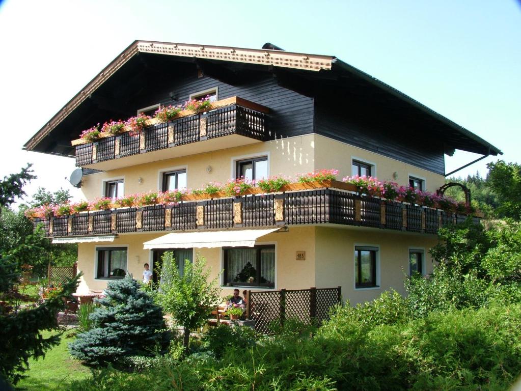 una casa con fiori sui balconi di Pension Windinger a Schiefling am Wörthersee