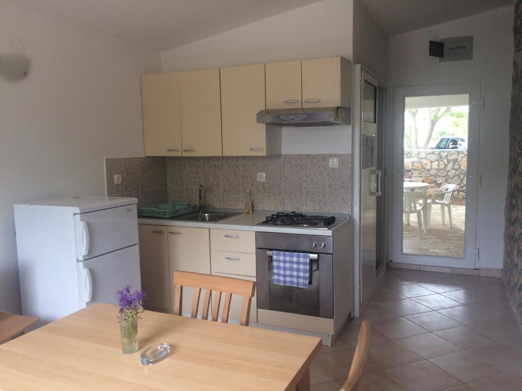 a kitchen with white appliances and a wooden table with a tableablish at Studio Apartment Bosko in Novalja