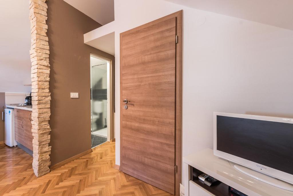 a living room with a television and a wooden door at Apartments Donat in Zadar