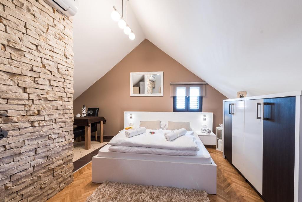 um quarto com uma cama branca e uma parede de tijolos em Apartments Donat em Zadar
