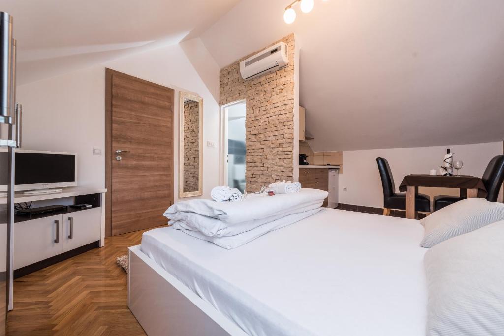 a bedroom with a large white bed and a television at Apartments Donat in Zadar
