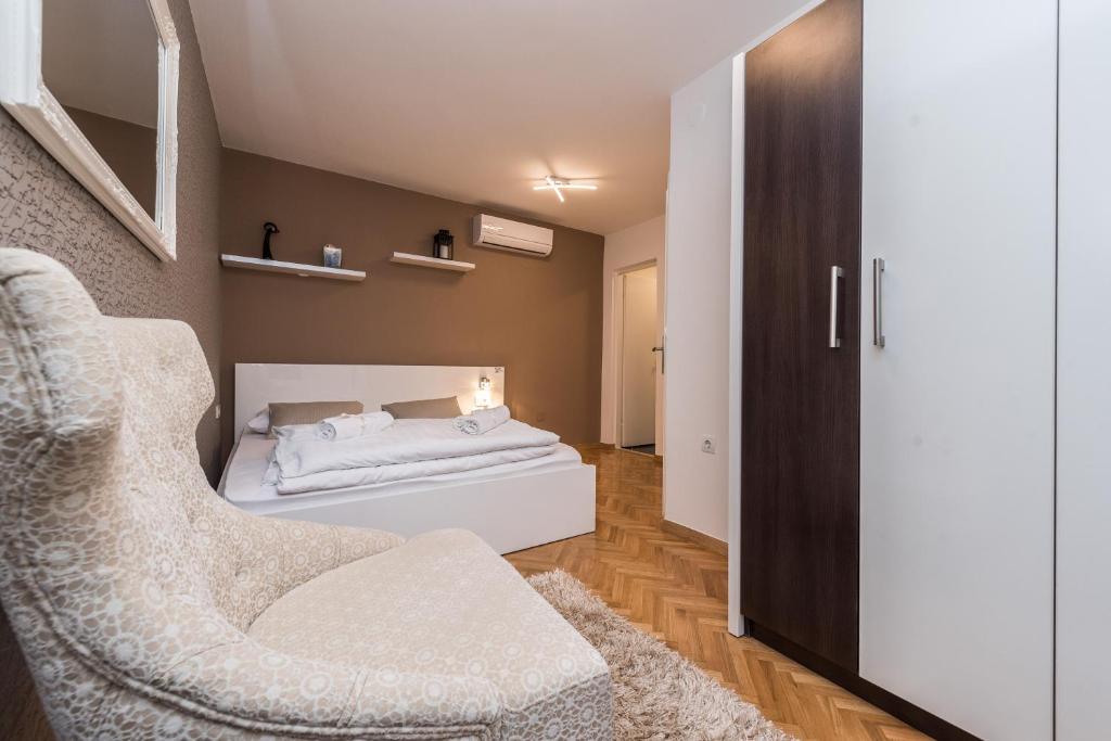 a small bedroom with a bed and a chair at Apartments Donat in Zadar