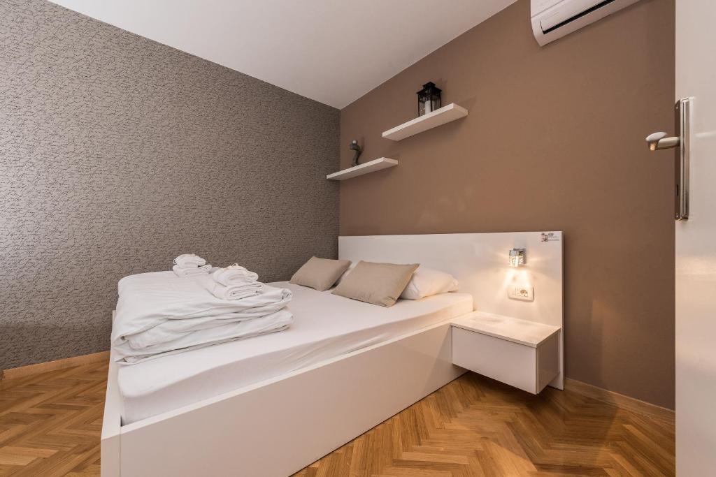 a small room with a white bed and shelves at Apartments Donat in Zadar