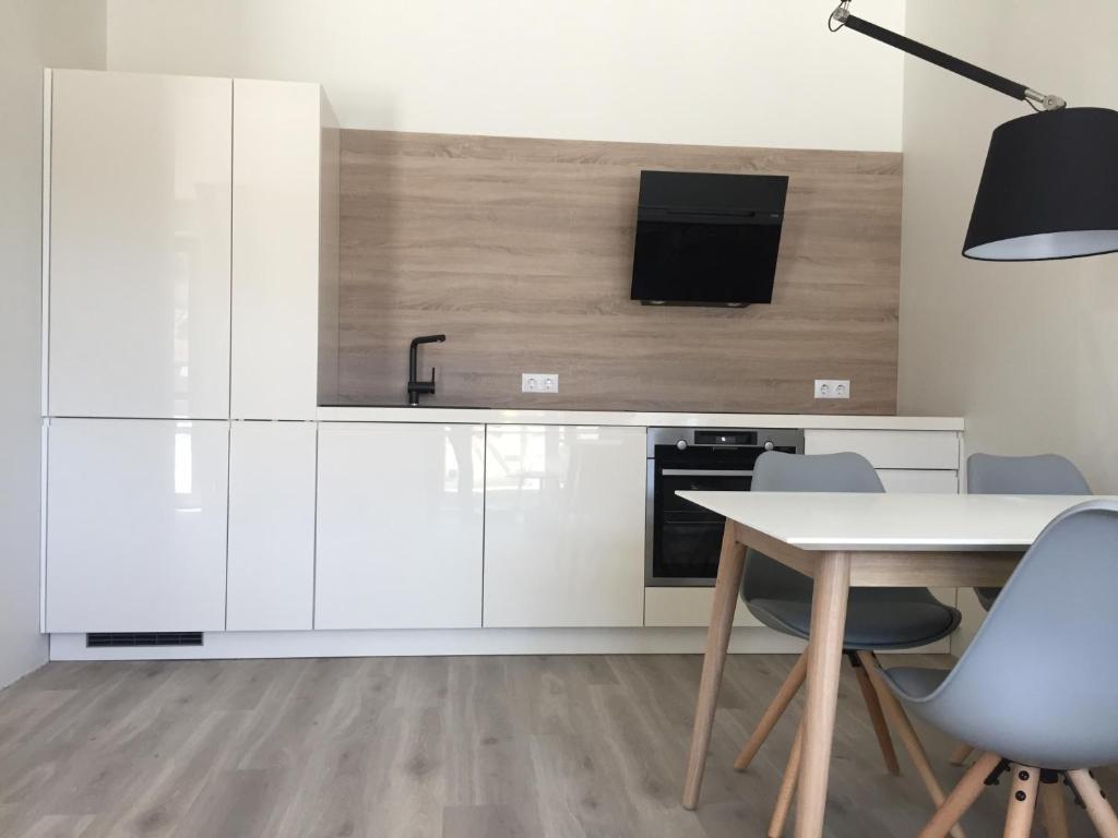 a kitchen with white cabinets and a table and chairs at Memel home old city apartment in Klaipėda