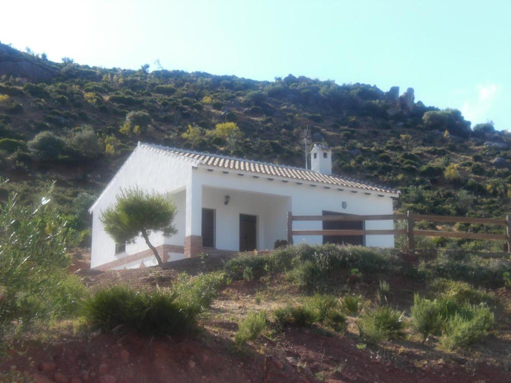 una pequeña casa blanca en la cima de una colina en La solana de turon. El pino, en Ardales