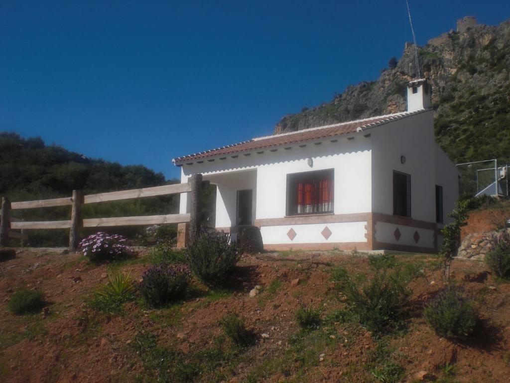 ein kleines weißes Haus auf einem Hügel mit einem Zaun in der Unterkunft La Solana de turón. La coscoja. in Ardales