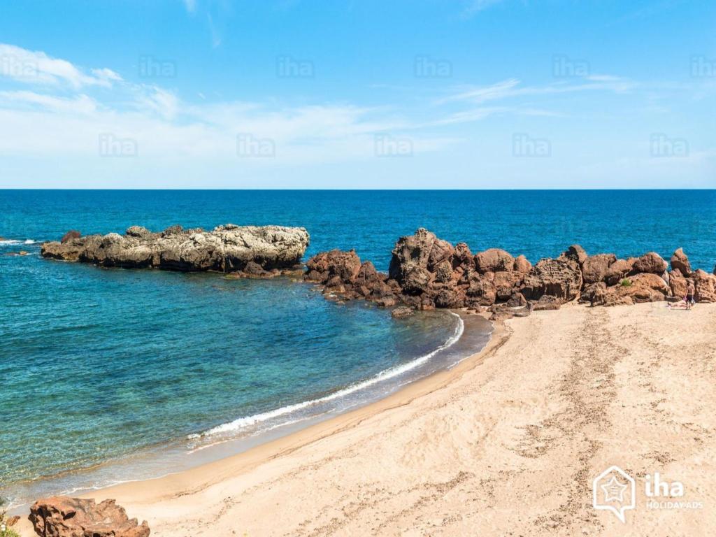 a sandy beach with rocks and the ocean at Casa VeroSol in Castelsardo