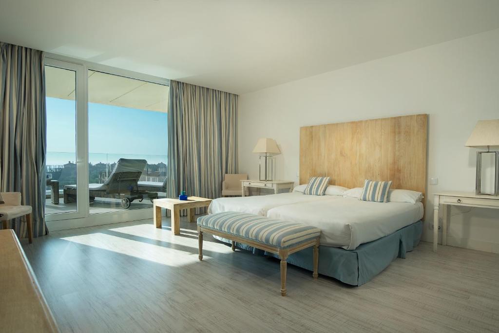 a hotel room with a bed and a balcony at Suites Puerto Sherry in El Puerto de Santa María