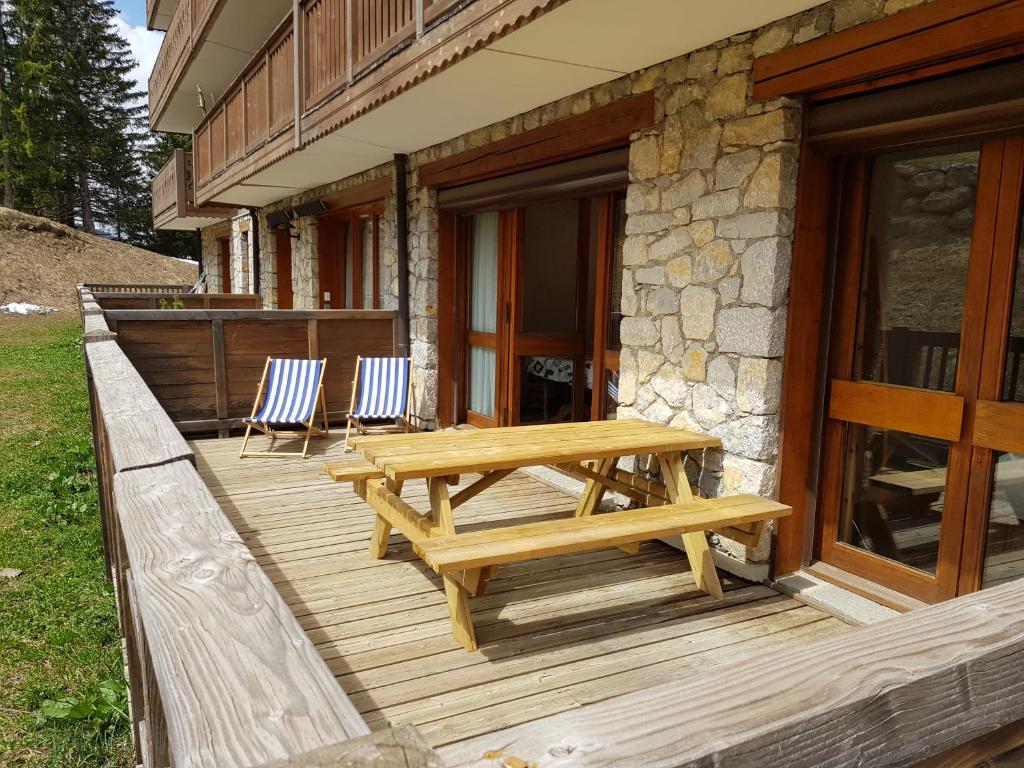 a wooden deck with a picnic table and two chairs at Un été à Courchevel in Courchevel