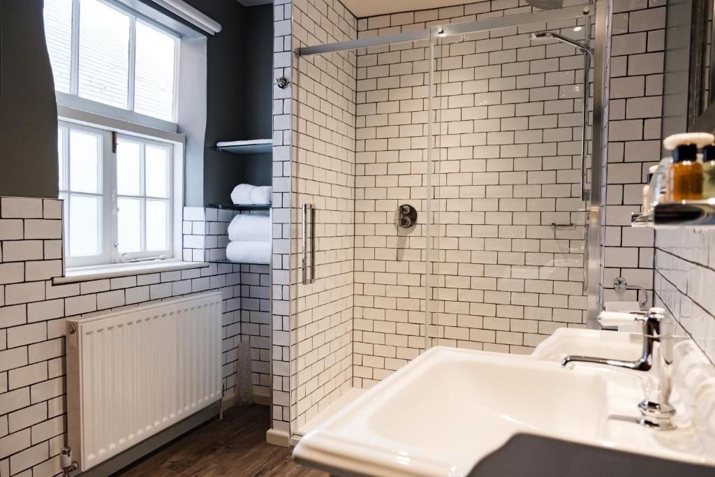 a white tiled bathroom with a sink and a window at Wykeham Arms in Winchester