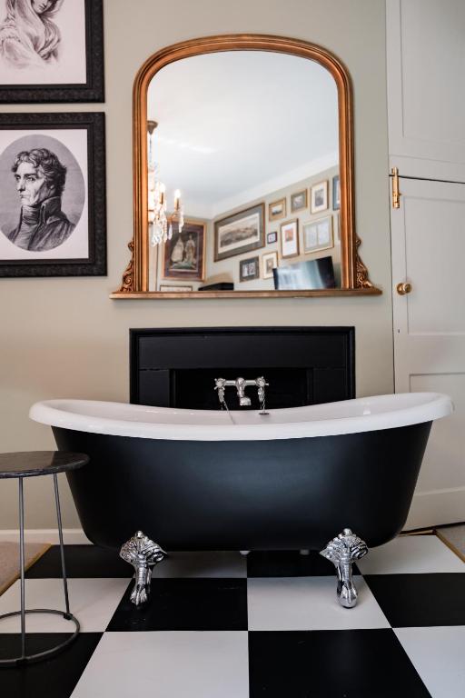 a black and white bathroom with a tub and a mirror at Wykeham Arms in Winchester