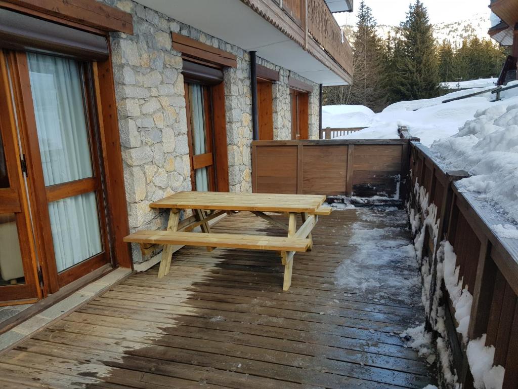 a wooden bench sitting on a wooden deck in the snow at Un hiver à Courchevel - Ski in ski out in Courchevel