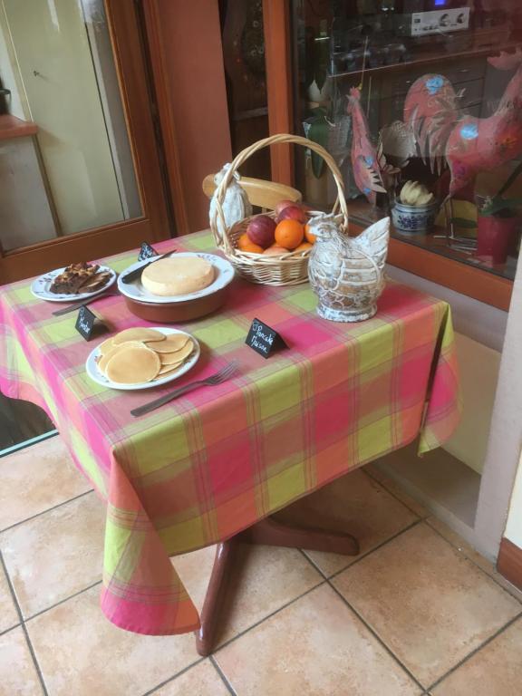 a table with a table cloth and a basket of fruit at Hôtel aux Bruyères in Orbey