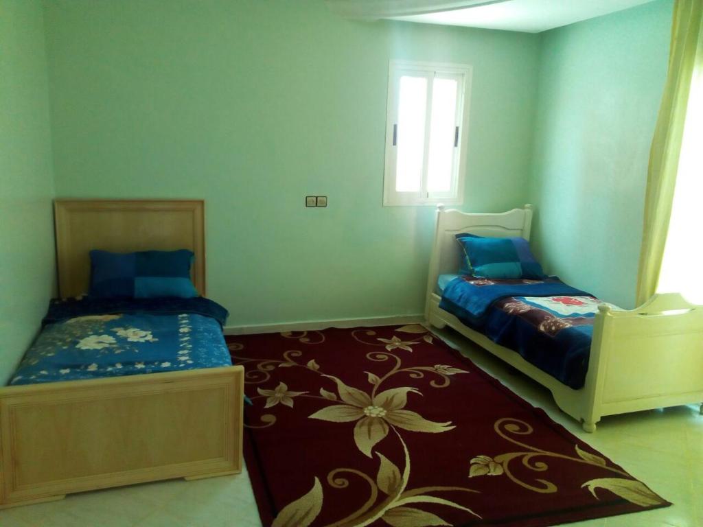 1 Schlafzimmer mit 2 Betten und einem Fenster in der Unterkunft villa avec jardin in Saidia 