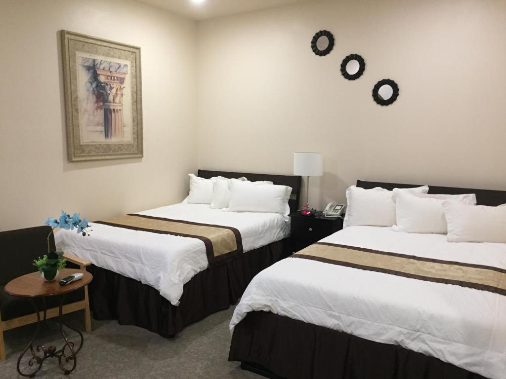 a hotel room with two beds and a clock on the wall at Geyser Inn in West Yellowstone