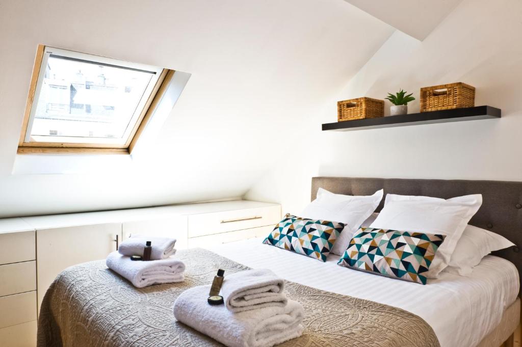 - une chambre avec 2 lits, des serviettes et une fenêtre dans l'établissement Pick A Flat's Apartments in Batignolles - Rue Biot, à Paris