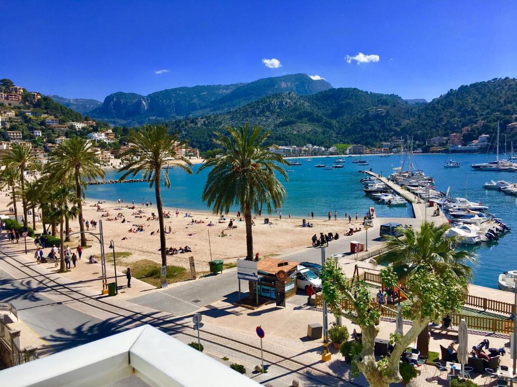 a beach with palm trees and people on the beach at Hotel Miramar in Port de Soller