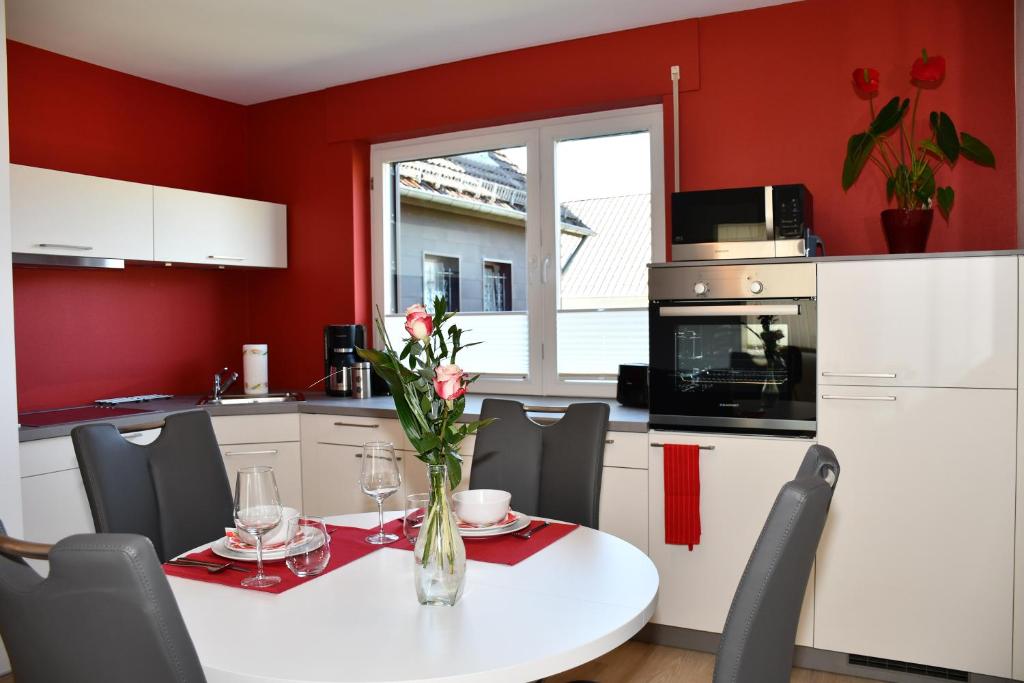 una cocina con paredes rojas y una mesa con un jarrón de flores en Eifellounge, en Monschau