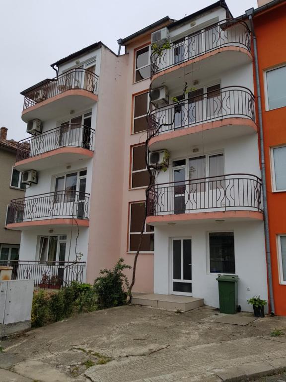 an apartment building with balconies and a parking lot at Хотел Милев in Kiten