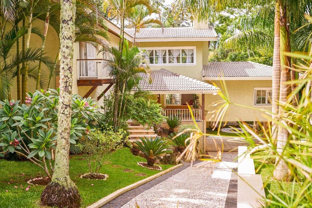 a house with palm trees and a walkway in front of it at Chácara Familiar Próximo a Buffets in Mairiporã