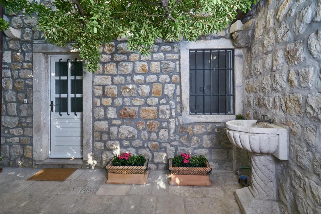 une maison en pierre avec un évier et deux plantes en pot dans l'établissement Apartments Olaf, à Dubrovnik