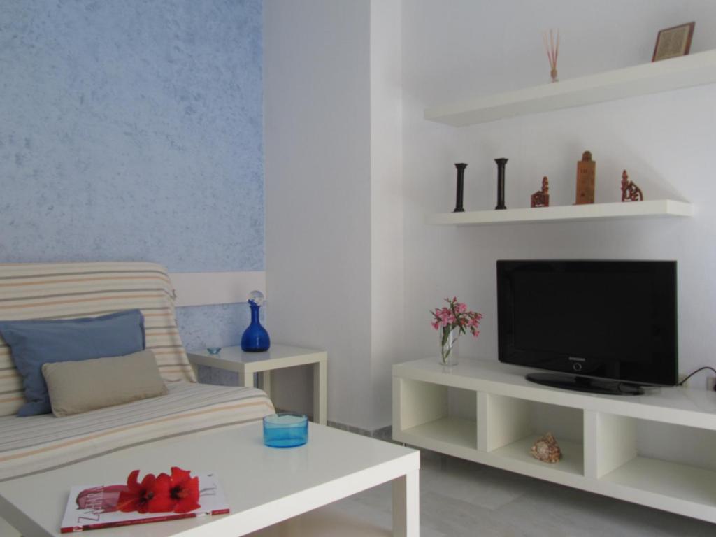 ein Wohnzimmer mit einem TV und einem Sofa in der Unterkunft Las Casas de Mar Zahara de los Atunes in Zahara de los Atunes
