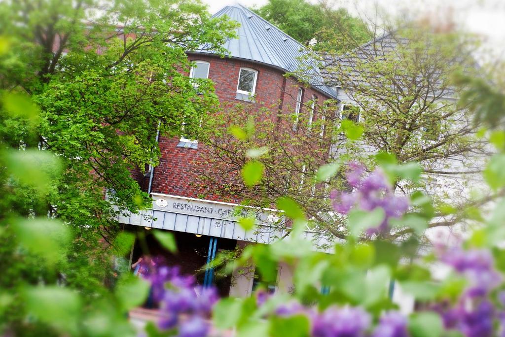 ein rotes Backsteingebäude mit einer Brücke vor den Blumen in der Unterkunft Hotel Quellenhof in Mölln