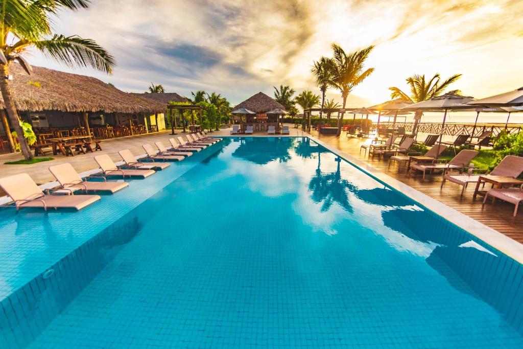 a pool at a resort with lounge chairs and palm trees at Manati in Barra Grande
