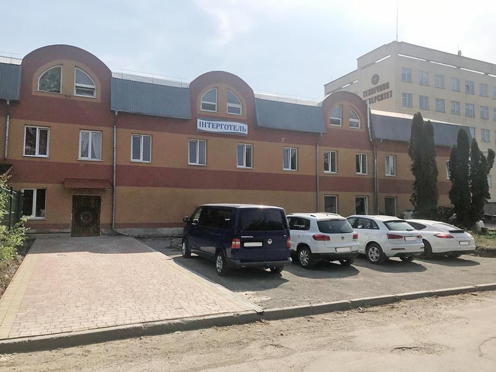 a building with cars parked in a parking lot at Inter Hotel in Ternopilʼ