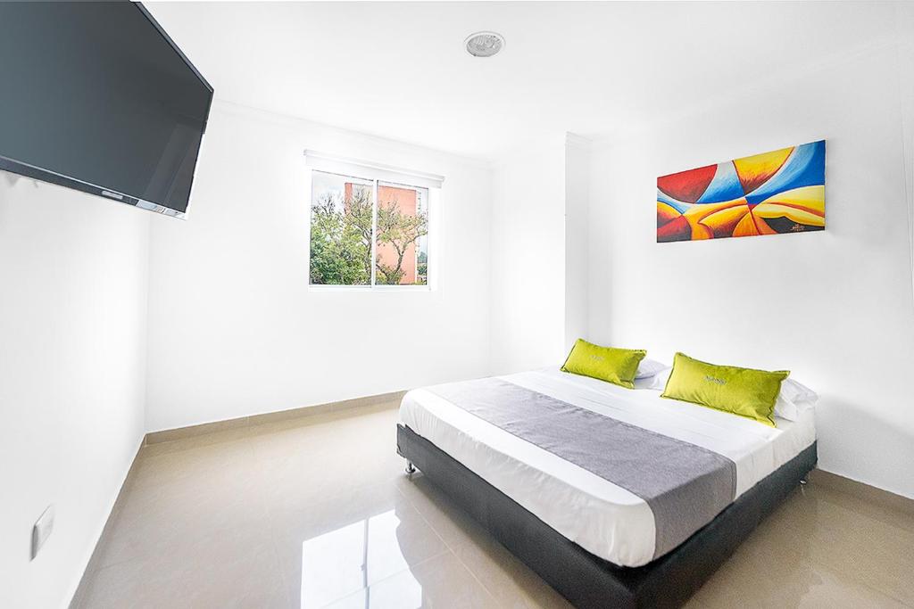 biała sypialnia z łóżkiem i dwoma obrazami na ścianie w obiekcie Ayenda 1219 Park 6 w mieście Medellín