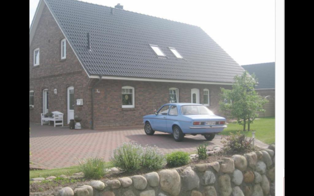 un coche azul estacionado frente a una casa de ladrillo en Ferienwohnung Petersen, en Nordstrand