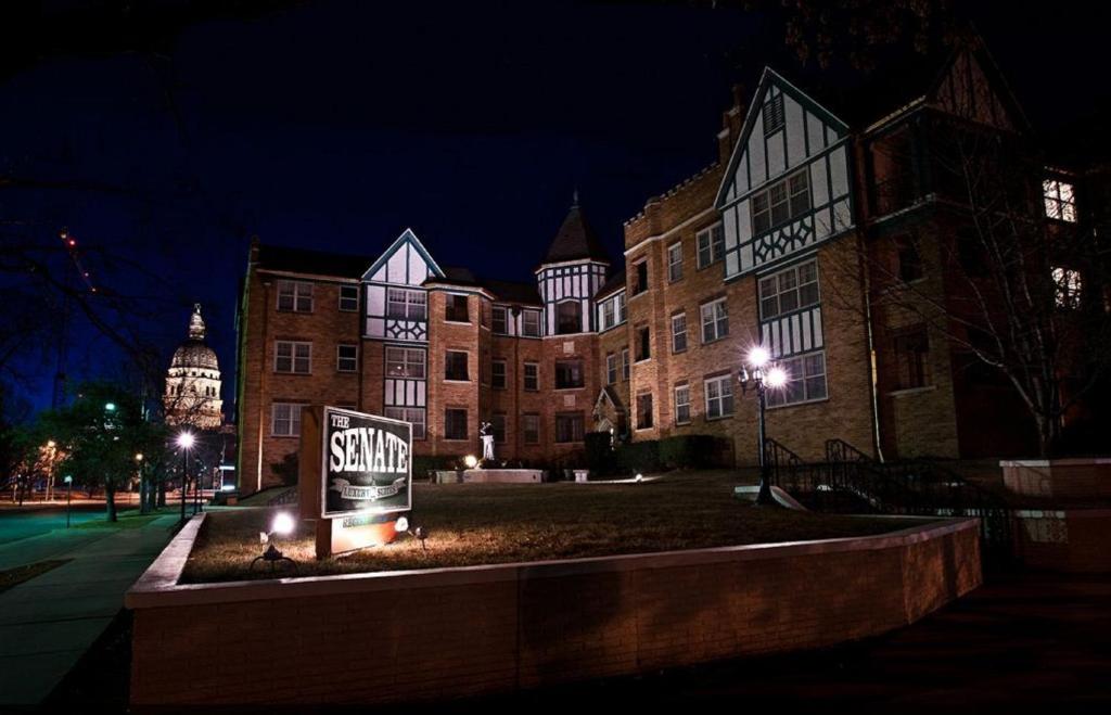 a large building with a sign in front of it at night at Senate Luxury Suites in Topeka