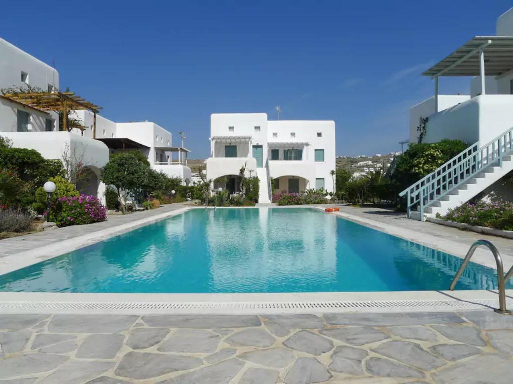 a swimming pool in front of some white houses at Mykonian Aroma House in Ornos