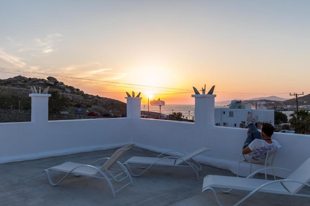 Un uomo seduto su un tetto che guarda il tramonto di Pension Alexandra Mykonos port a Mykonos Città