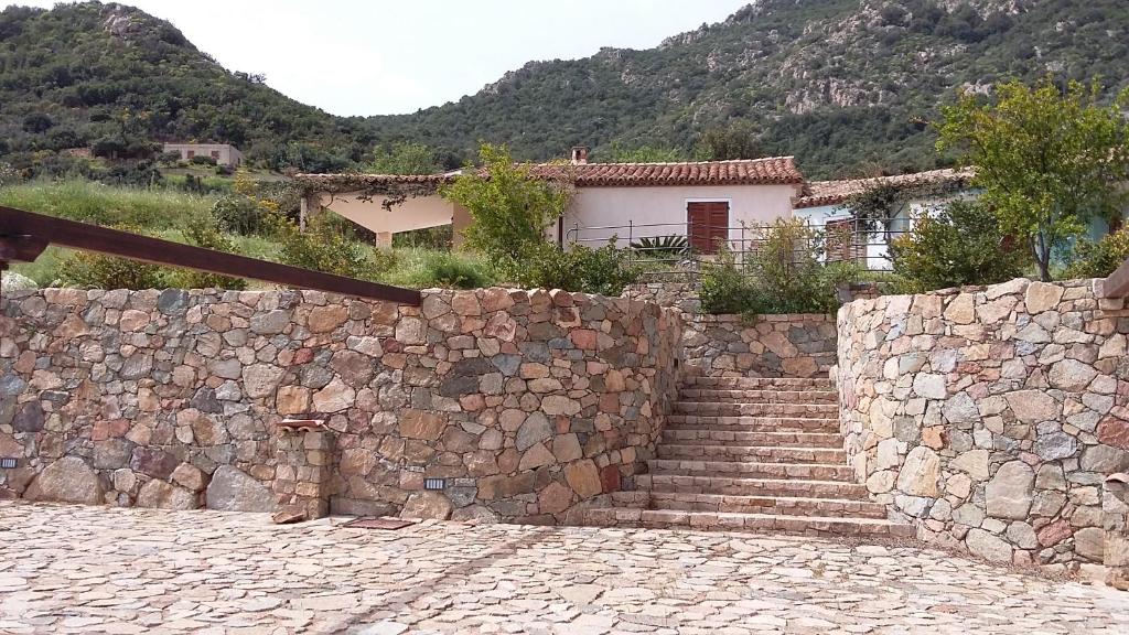 a stone wall with stairs and a house in the background at la casetta rosa in Tertenìa