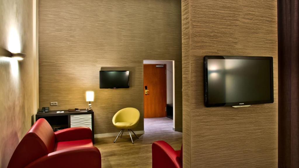 a hotel room with a tv and red chairs at Artim Hotel in Berlin