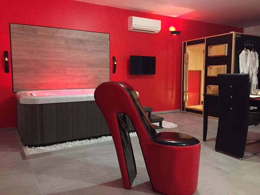 a red room with a chair and a mirror at La Paillote Exotique Spa in Beaucaire