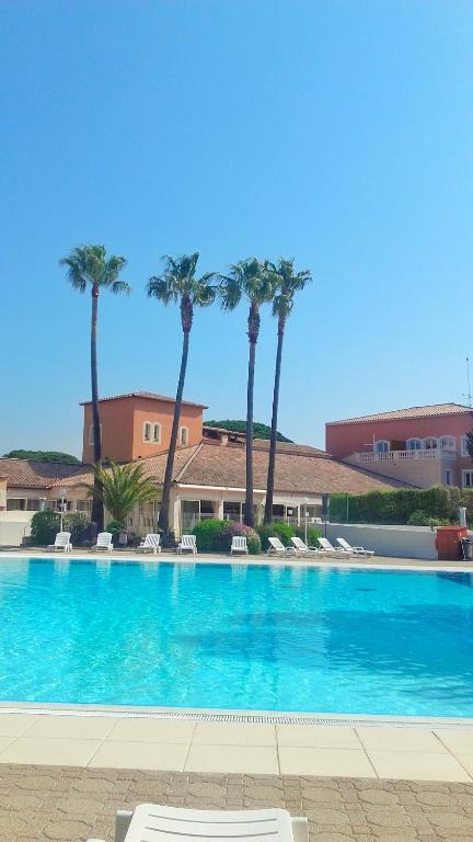 une grande piscine avec des palmiers en arrière-plan dans l'établissement Résidence Golfs de Valescure 9, à Saint-Raphaël