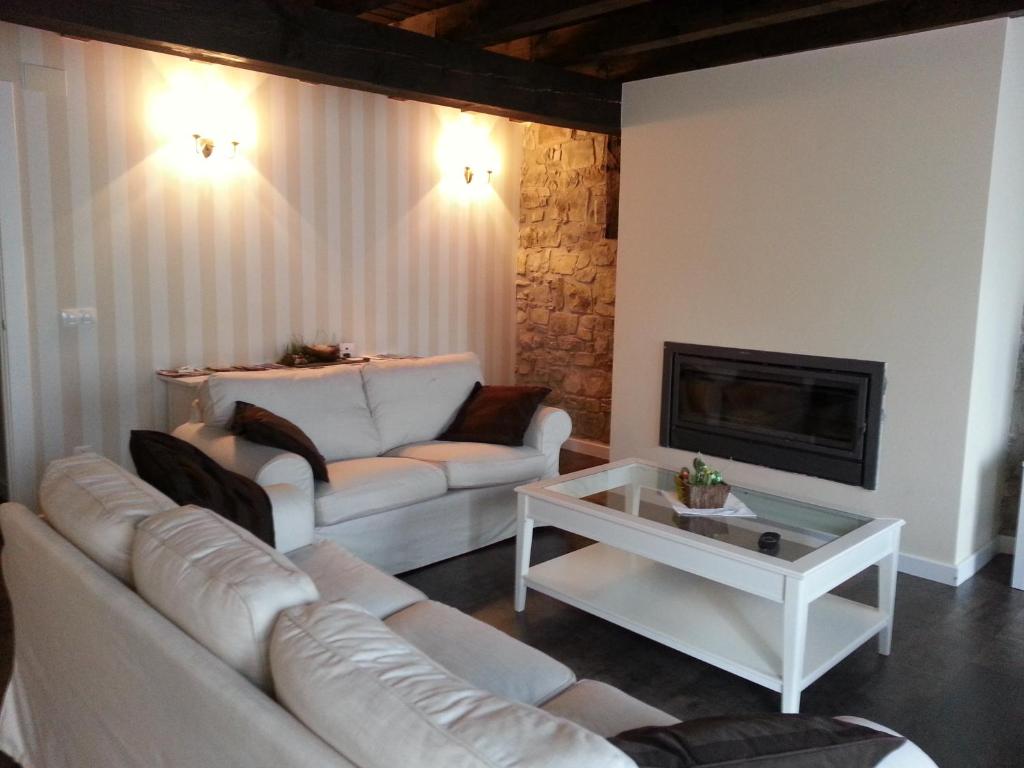 a living room with white couches and a fireplace at Casa Rural el Rincon de Maria in Villoslada de Cameros