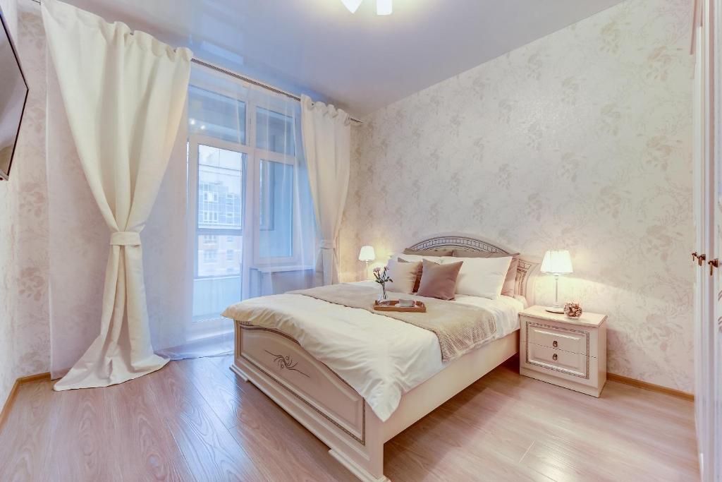 a white bedroom with a bed and a window at Апартаменты Веста в ЖК Премьер Палас in Saint Petersburg