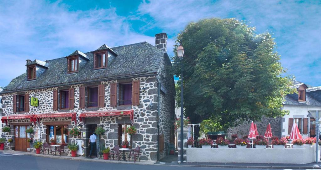 een stenen gebouw met rode accenten in een straat bij Hotel De La Poste in Saint-Martin-sous-Vigouroux