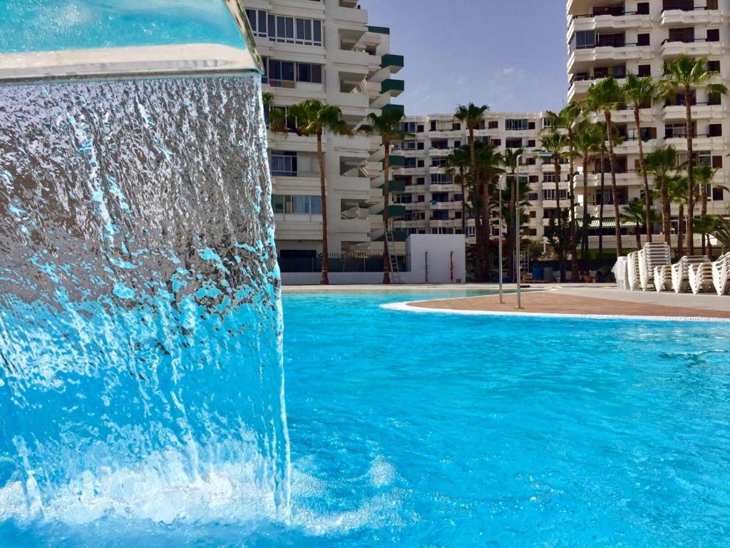 a water fountain in a pool with buildings in the background at OHMYHOST360 - Sunny Home Holidays in Playa del Ingles