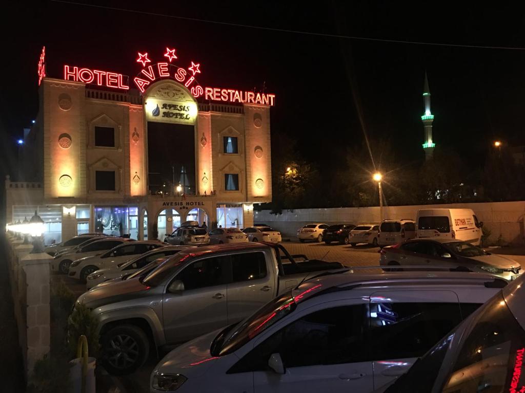 Avesis Hotel في نصيبين: فندق فيه سيارات متوقفة في مواقف بالليل
