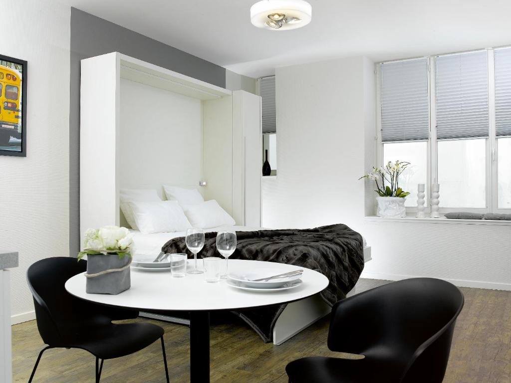 a living room with a table and chairs and a bed at Appartements Le 32 in Strasbourg