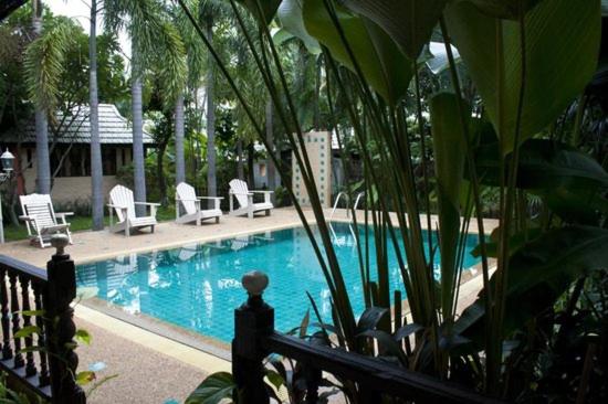 a swimming pool with white chairs and a fence at The Royal Shilton Resort in Chiang Mai