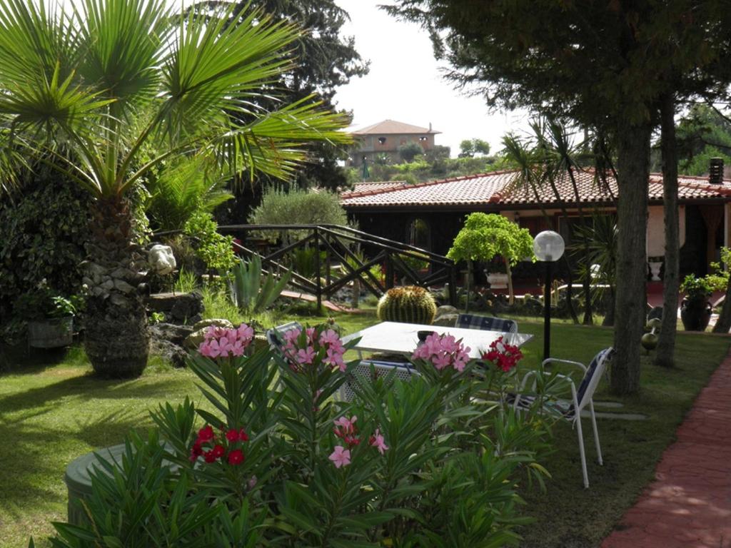 une table et des chaises dans un jardin fleuri dans l'établissement Parco Delle Tre Fontane, à Nicolosi