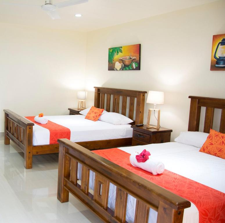 a bedroom with three beds with orange and white sheets at Samoana Boutique Hotel in Apia