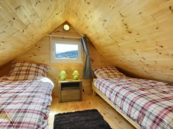 two beds in a wooden cabin with a window at Domki Złoty Widok in Sosnówka