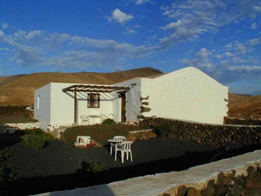 ein weißes Haus mit einem Tisch und Stühlen davor in der Unterkunft GBH Casas Fimbapaire in La Oliva